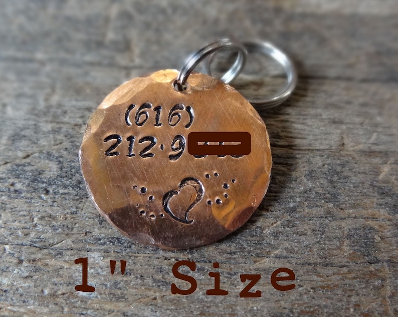May include: A 1 inch copper dog tag with a hammered finish. The tag has a heart design and the text (616) 212-9---.