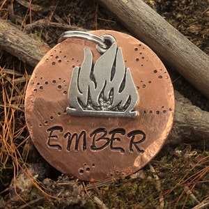 May include: Copper dog tag with a silver flame design and the word "EMBER" engraved on it.