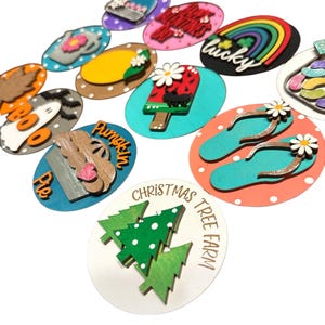 May include: A set of 12 wooden ornaments with various designs, including a pumpkin pie, a Christmas tree, a rainbow, and a popsicle. The ornaments are painted in bright colors and have a polka dot background.