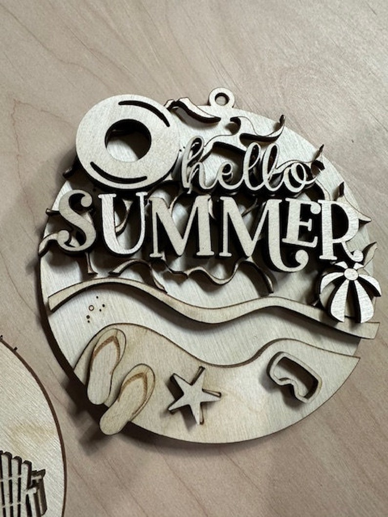 May include: Wooden cutout of a beach scene with the words "hello summer" in the center. The scene includes a life preserver, flip flops, a starfish, a diving mask, and a beach ball.