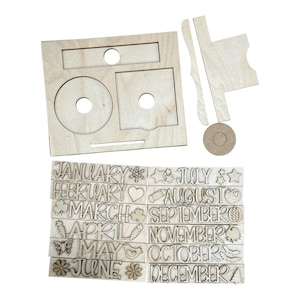 May include: A light-colored wooden craft kit featuring a rectangular base with cutouts, a stand, and twelve rectangular wooden pieces engraved with the names of the months from January to December, each accompanied by a seasonal icon.