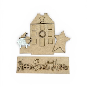 May include: A wooden home decor set featuring a house, star, sheep, and the phrase "Home Sweet Home." The house has windows, a star on top, and a wreath. The sheep has a patterned design. The set is made of unfinished wood.