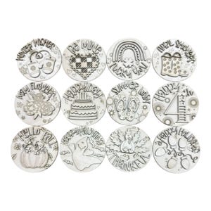 May include: Twelve circular wooden discs featuring seasonal designs and text. The set includes Winter Wishes, Be Mine, Lucky You, April Showers, May Flowers, Happy Day, Summer Lovin, Happy 4th, Hello Fall, Happy Haunting, Be Thankful, and Happy Holidays.