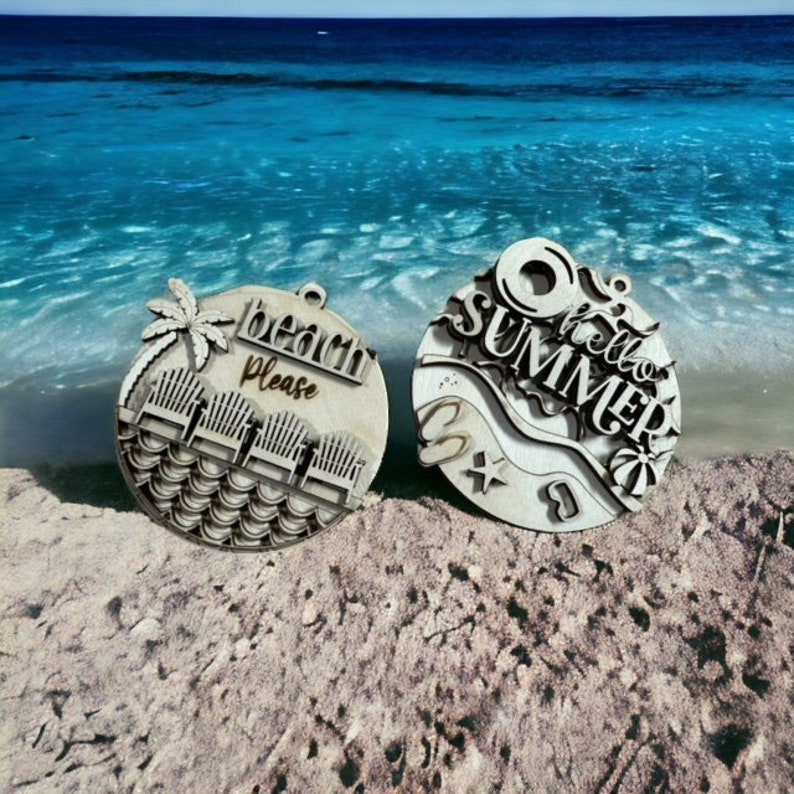 May include: Two wooden ornaments with summer themes. One ornament features the text "beach please" with a palm tree and beach chairs. The other ornament features the text "hello summer" with a beach umbrella, a starfish, and a wave.