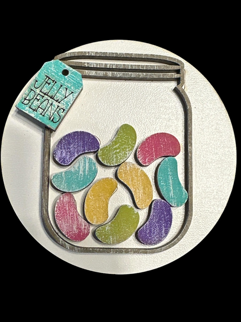 May include: A wooden cutout of a mason jar filled with colorful jelly beans. The jar has a tag that says "Jelly Beans".
