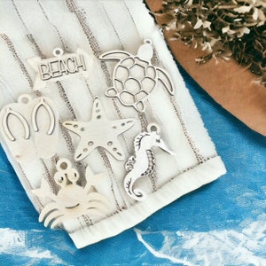 May include: A set of six wooden ornaments with a beach theme. The ornaments are shaped like a turtle, starfish, seahorse, flip flops, crab, and a sign that says "Beach".