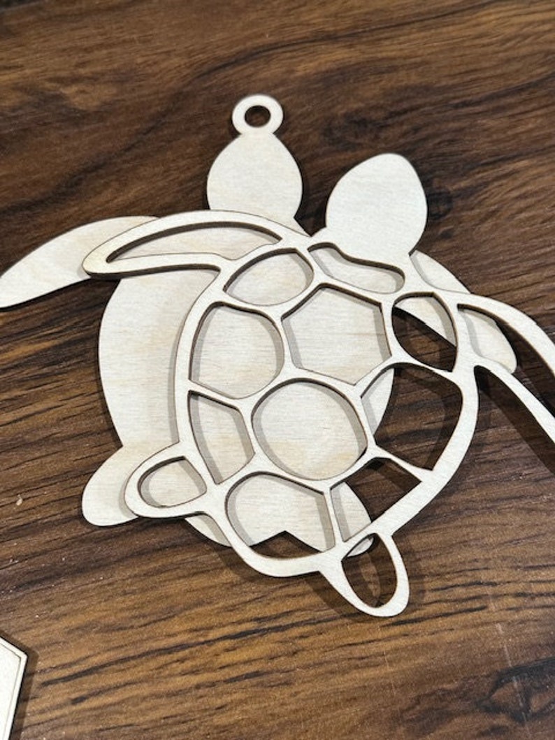 May include: A wooden cutout of two sea turtles, one on top of the other. The top turtle has a detailed shell design.