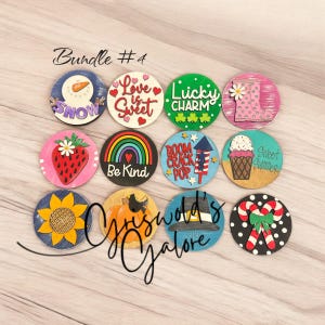 May include: A collection of twelve wooden round ornaments with various designs and text. Designs include a snowman, hearts, shamrocks, a boot, a strawberry, a rainbow, fireworks, an ice cream cone, a sunflower, a pumpkin, a pilgrim hat, and candy canes. The text includes "Bundle #4", "Love is Sweet", "Lucky Charm", "Be Kind", "Boom Crack Pop", and "Sweet Summer".