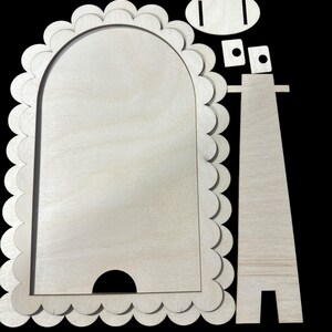 May include: A wooden picture frame with a scalloped edge and a stand. The frame is unfinished and ready to be painted or stained.
