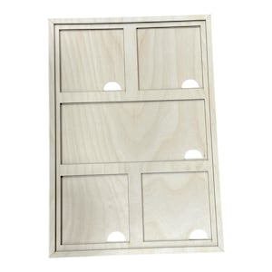 May include: A light-colored wooden organizer with a rectangular frame. It features six compartments of varying sizes, each with a semi-circular cutout. The wood grain is visible, giving it a natural look.
