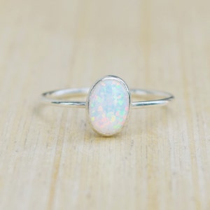 May include: A silver ring with a white opal gemstone. The ring is simple and elegant, perfect for everyday wear.