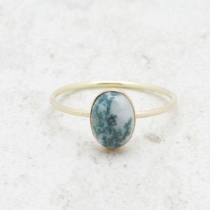 May include: A gold ring with a green and white oval agate stone.