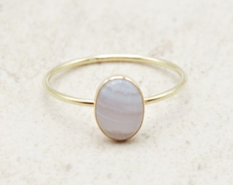 May include: A gold ring with a white agate oval stone set in the center.