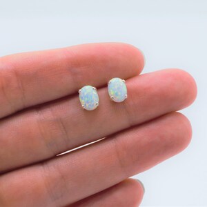Puede incluir: Un par de pendientes de plata con opales blancos de forma ovalada.