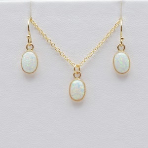 May include: A gold necklace and earrings set with oval-shaped white opal stones.