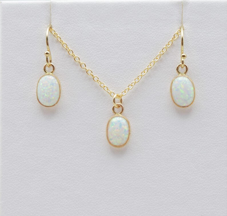 May include: A gold necklace and earrings set with oval-shaped white opal stones.