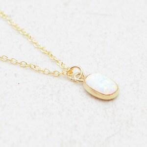 May include: A delicate gold chain necklace with a small oval opal pendant.