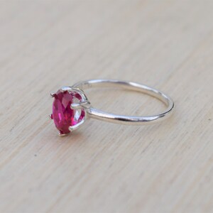 May include: A silver ring with a large, oval-shaped, bright pink gemstone set in a prong setting.