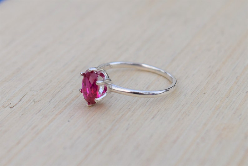 May include: A silver ring with a large, oval-shaped, bright pink gemstone set in a prong setting.