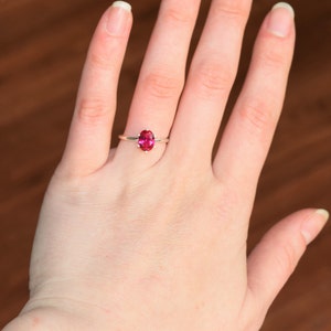 May include: A silver ring with a pink oval gemstone.