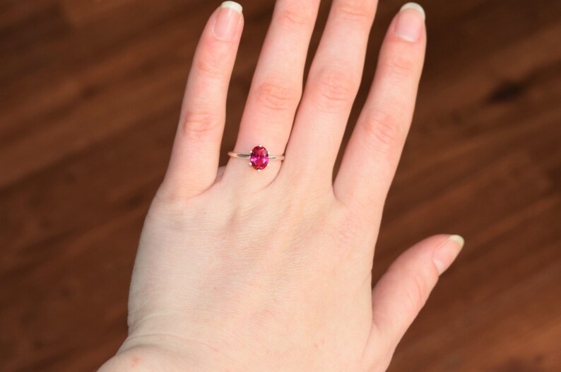 May include: A silver ring with a pink oval gemstone.