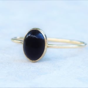 May include: A gold ring with a black oval gemstone.
