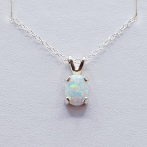 Puede incluir: Un collar de cadena de plata con un colgante de &oacute;palo blanco. El &oacute;palo tiene forma ovalada y tiene un delicado engaste de plata.