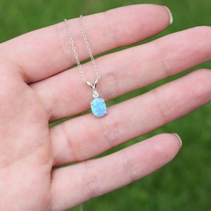 May include: A silver chain necklace with a light blue oval opal pendant.