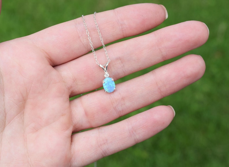 May include: A silver chain necklace with a light blue oval opal pendant.