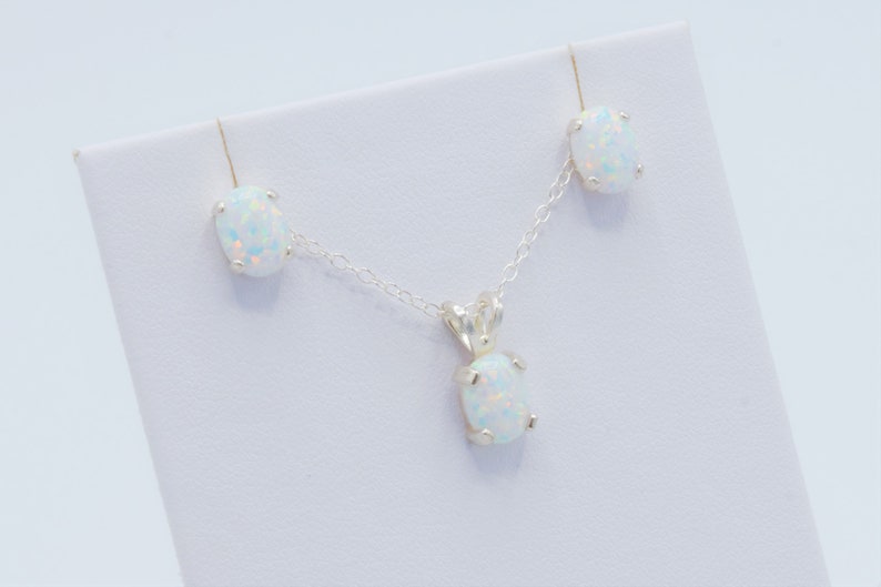 Puede incluir: Un conjunto de collar y pendientes de plata con piedras de &oacute;palo blanco. El collar presenta un colgante con una piedra de &oacute;palo blanco y una cadena de plata. Los pendientes son de plata con piedras de &oacute;palo blanco.
