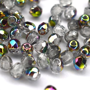 Op de afbeelding: Een strooiing van regenboogkleurige glazen kralen met een heldere glazen afwerking. De kralen zijn rond en hebben een facetgeslepen ontwerp.