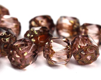 May include: A group of 12 iridescent brown glass beads with a faceted design. The beads have a clear center with a brown iridescent coating.
