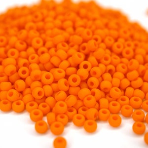 Könnte beinhalten: Ein Haufen kleiner, runder, orangefarbener Perlen. Die Perlen sind undurchsichtig und haben eine glatte, matte Oberfläche.
