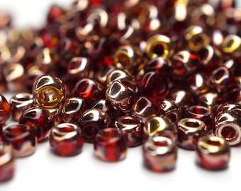 May include: A pile of small, round, red and gold glass beads. The beads have a shiny, iridescent finish.
