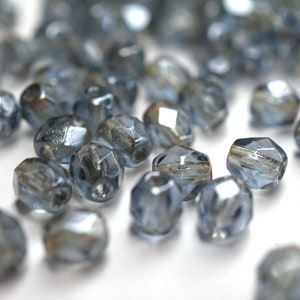 Könnte beinhalten: Eine Streuung kleiner, facettierter Glasperlen in hellblau mit einem metallischen Schimmer.