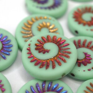 Könnte beinhalten: Sortiment runder, grüner Glasperlen mit einem Spiralmuster in Violett-, Rot- und Goldtönen. Die Perlen haben eine glänzende Oberfläche.