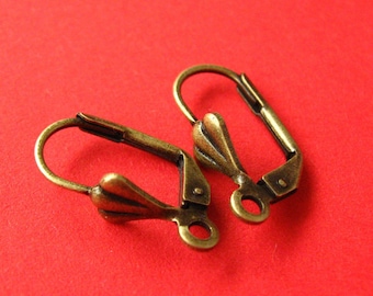 May include: A pair of antique gold-toned earring hooks with a decorative leaf design. The hooks are made of metal and have a spring-loaded closure.