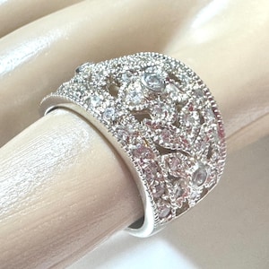 May include: A white ceramic mug with a colorful floral design. The mug features a variety of flowers in shades of pink, purple, and yellow. The mug is approximately 4 inches tall.