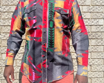 May include: A long-sleeved button-down shirt with a geometric pattern in shades of red, yellow, green, and black on a gray background. The shirt has two chest pockets and a button-down collar.