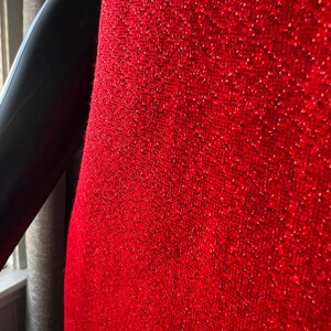 May include: Close-up of a red fabric with a textured, sparkly surface.