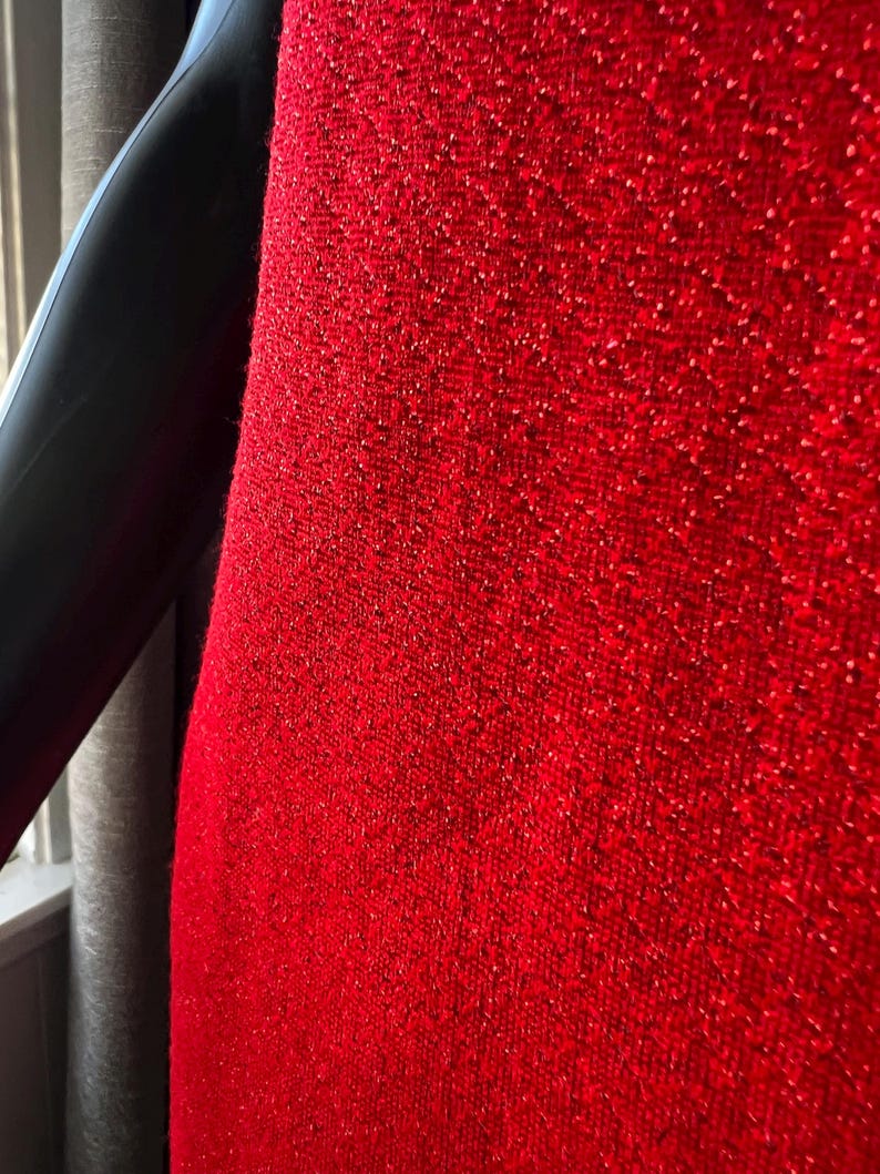 May include: Close-up of a red fabric with a textured, sparkly surface.