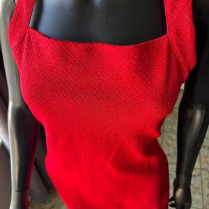 May include: A red sleeveless dress with a square neckline and a sparkly texture.