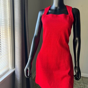 May include: A sleeveless red dress with a square neckline. The dress is made of a textured fabric.