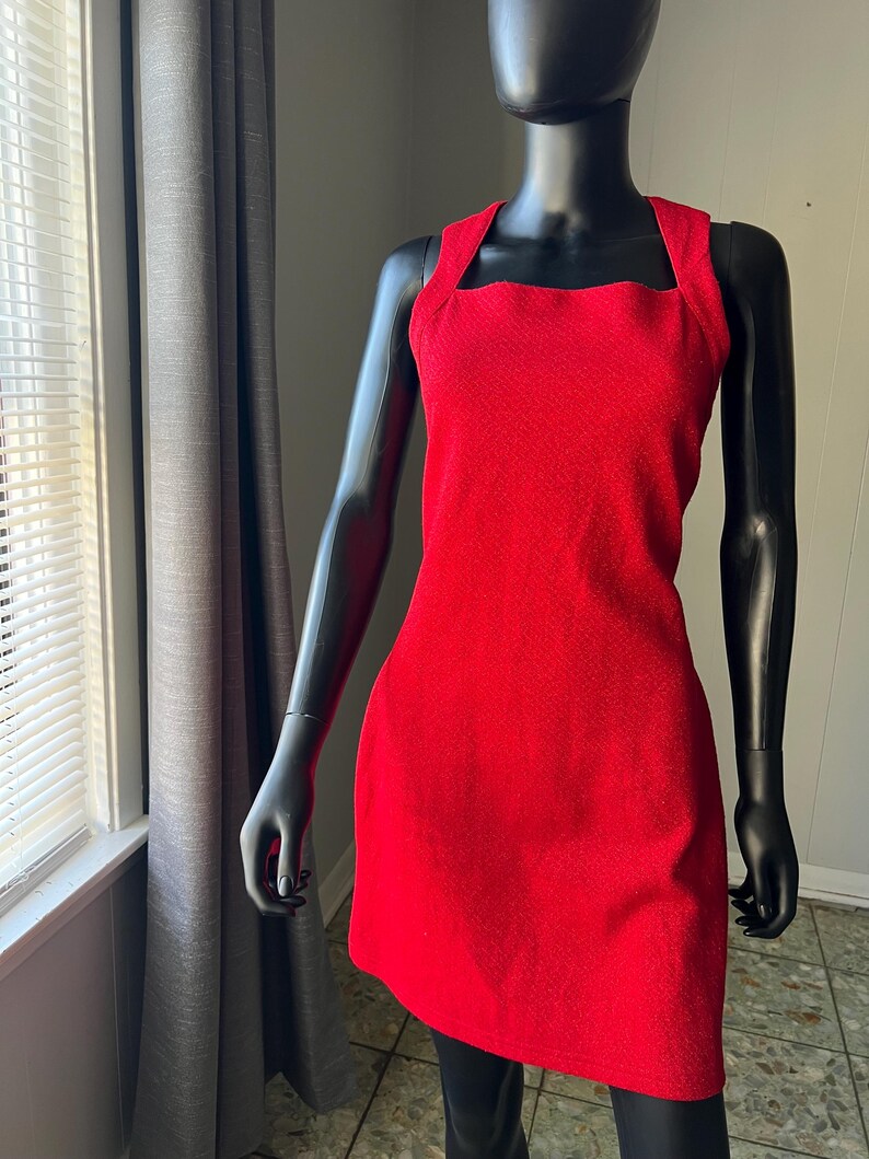 May include: A sleeveless red dress with a square neckline. The dress is made of a textured fabric.
