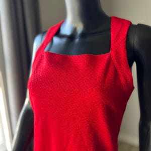 May include: A sleeveless red dress with a square neckline and a textured fabric.