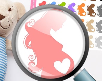 May include: A sheet of colorful pregnancy tracker stickers featuring a silhouette of a pregnant person with a heart. The stickers are in various colors, including red, blue, green, and orange. A plush teddy bear is in the background.