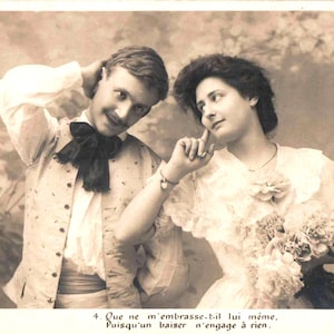 May include: Sepia-toned vintage postcard featuring a man and a woman. The man wears a white shirt, vest, and a large black bow tie. The woman is in a lace dress and holds flowers. Text at the bottom reads in French.