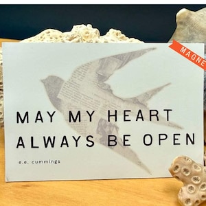 May include: A rectangular magnet with the text "MAY MY HEART ALWAYS BE OPEN" and "e.e. cummings" printed in black. A bird illustration is visible behind the text. The magnet has a red "MAGNET" label in the upper right corner.