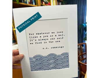 May include: A white framed print with a blue and white wave pattern at the bottom. The print features a poem by e.e. cummings that reads "For whatever we lose (like a you or a me), It's always our self we find in the sea".