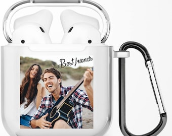 Puede incluir: Estuche transparente de plástico para auriculares inalámbricos con mosquetón. El estuche tiene una foto de dos amigos en una playa, uno tocando la guitarra. El texto "Best Friends" está impreso en el estuche.